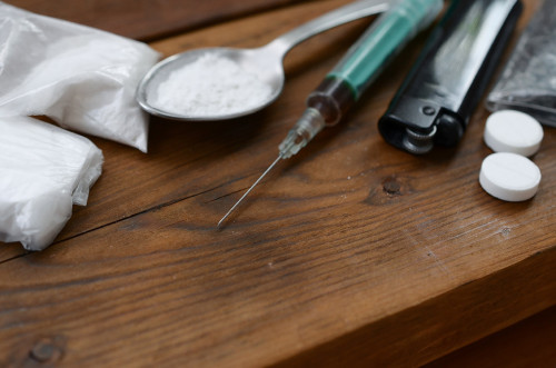 A lot of narcotic substances and devices for the preparation of drugs lie on an old wooden table. Drug dealer stuff. Heroin and methamphetamine in raw condition. Narcotic addiction concept