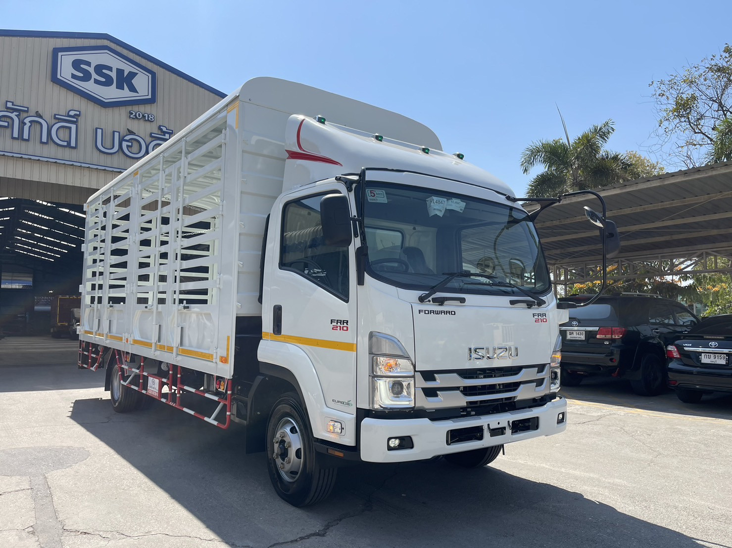รถบรรทุก Isuzu FRR สีขาว พร้อมกระบะคอกสำหรับขนส่งน้ำ